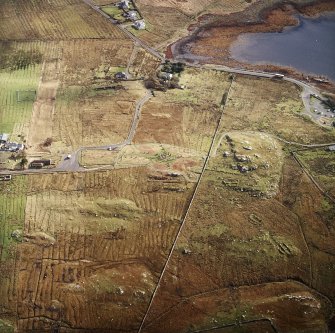 Oblique aerial view centred on the remains of the stone circle, chambered cairn and stone alignments with the township and lazy beds adjacent, taken from the W.