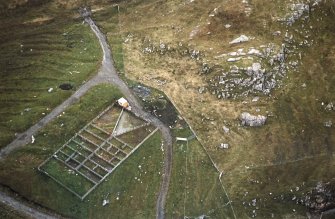 Oblique aerial view centred on the reconstructed shieling hut and sheep pen, taken from the NNW.