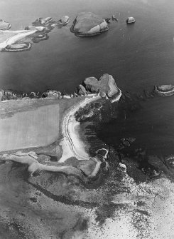 Oblique aerial view centred on the remains of the fort, settlement and lazy beds, with remains of rig cultivation adjacent, taken from the NW.