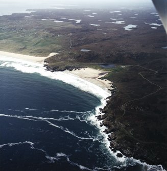 General oblique aerial view looking across Traigh Gearadha beach, the remains of the dun, possible promontory fort and lazy beds taken from the NE.