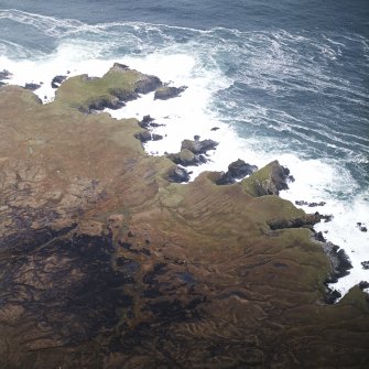 Oblique aerial view centred on the remains of the possible promontory forts and lazy beds, taken from the SSW.
