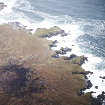 Oblique aerial view centred on the remains of the possible promontory forts and lazy beds, taken from the S.