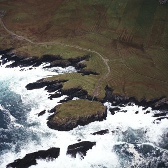 Oblique aerial view centred on the remains of the settlement with the remains of lazy beds adjacent, taken from the NNE.