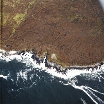 Oblique aerial view centred on the remains of the chambered cairn, taken from the NW.