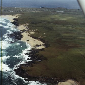 General oblique aerial view looking across the remains of the dun, building and the lazy beds along the west coast of Lewis towards Eoropie, taken from the WSW.