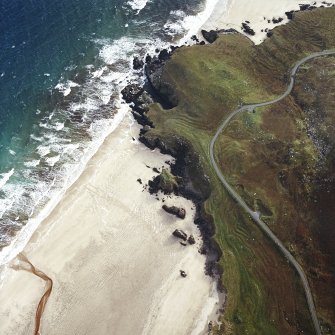 Oblique aerial view centred on the remains of the dun with the remains of the possible promontory fort, lazy beds and possible shieling-hut adjacent, taken from the NW.