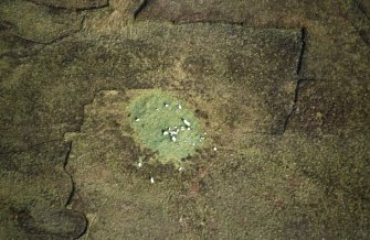 Oblique aerial view centred on the remains of the chambered cairn, taken from the SW.