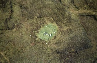 Oblique aerial view centred on the remains of the chambered cairn, taken from the SSE.