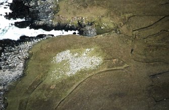 Oblique aerial view centred on the remains of the chambered cairn, taken from the SW.