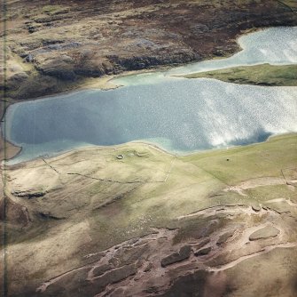 Oblique aerial view centred on the remains of the possible dun, longhouses, buildings and enclosure with longhouse and possible farmstead adjacent, taken from the NW.