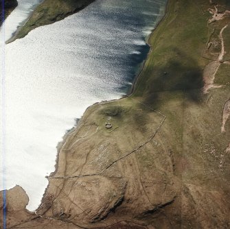 Oblique aerial view centred on the remains of the possible dun, longhouses, buildings and enclosure with longhouse, enclosure, possible farmstead and building adjacent, taken from the NE.