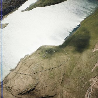 Oblique aerial view centred on the remains of the possible dun, longhouses, buildings and enclosure with longhouse, enclosure and possible farmstead adjacent, taken from the NNE.