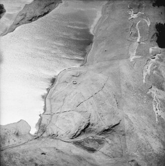 Oblique aerial view centred on the remains of the possible dun, longhouses, buildings and enclosure with longhouse, enclosure, possible farmstead and building adjacent, taken from the NE.