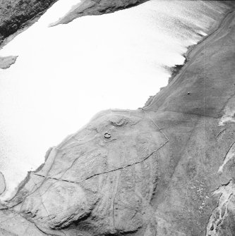 Oblique aerial view centred on the remains of the possible dun, longhouses, buildings and enclosure with longhouse, enclosure and possible farmstead adjacent, taken from the NNE.