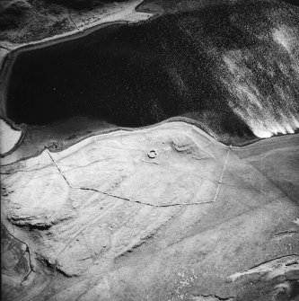 Oblique aerial view centred on the remains of the possible dun, longhouses, buildings and enclosure with longhouse adjacent, taken from the NW.