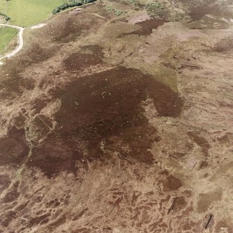 Cnoc Cairaidh, Achnagarron, oblique aerial view, taken from the E, centred on an area with hut-circles, a field-system and possible cord rig. Standing stones and a building are visible in the top left-hand corner of the photograph.