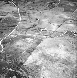 Breackue, oblique aerial view, taken from the NNE, showing an area with a hut-circle and small cairns in the centre of the photograph, and small cairns, a hut and mound in the upper left-hand corner.