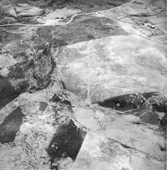 Breackue, Cnoc Dubh, oblique aerial view, taken from the NW, showing an area with small cairns and a trackway, a hut-circle and small cairns, as well as an enclosure, a hut and burnt mound in the centre of the photograph. An area with small cairns and a farmstead is visible in the upper left-hand corner.