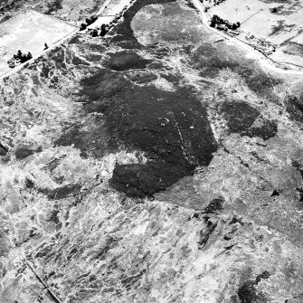 Cnoc Cairaidh, Achnagarron, oblique aerial view, taken from the NW, centred on an area with hut-circles, a field-system and possible cord rig. A hut-circle, small cairns and a building are visible in the top half of the photograph.