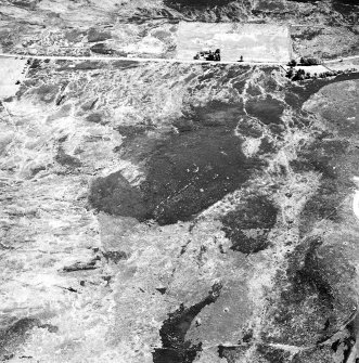 Cnoc Cairaidh, Glenelg, oblique aerial view, taken from the NW, centred on an area with hut-circles, a field-system and possible cord rig. A farmstead is visible in the top left-hand corner of the photograph.