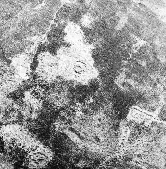 Oblique aerial view centred on the remains of the hut-circle and field system, taken from the SE.