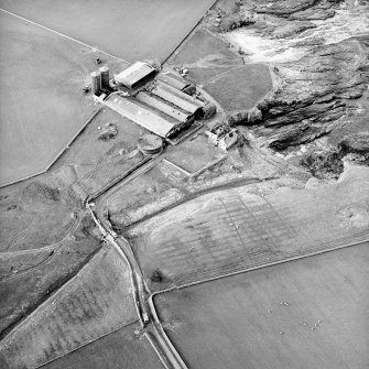 Oblique aerial view centred on the farmsteading and the remains of the tower-house, taken from the SE