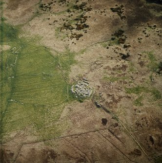 Oblique aerial view centred on the remains of the dun, settlement and field system with hut-circle and farmstead adjacent, taken from the NE.