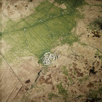 Oblique aerial view centred on the remains of the dun, settlement and field system with hut-circle and farmstead adjacent, taken from the NW.