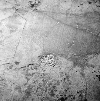 Oblique aerial view centred on the remains of the dun, settlement and field system with hut-circle and farmstead adjacent, taken from the WNW.