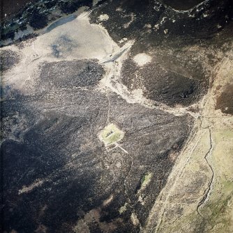 Oblique aerial view centred the remains of the chambered cairn and the dam, taken from the SE.