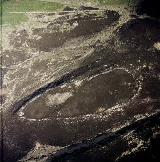 Oblique aerial view centred on the remains of the fort with cairn and stone rows adjacent, taken from the WNW.