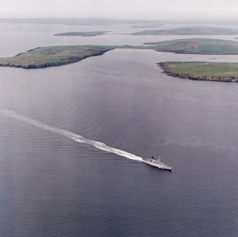 General oblique aerial view looking across a frigate in the Sound of Hoxa, towards South Ronaldsay and Mainland, taken from the SSW.