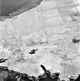 Stroma, oblique aerial view, taken from the W, showing Nethertown township in the centre of the photograph, and Bught o' Camm promontory fort in the bottom left-hand corner.