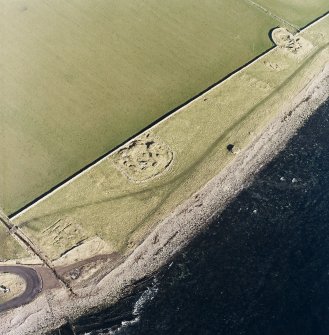 Oblique aerial view of the remains of the brochs, buildings, possible building, pillbox and slipway, taken from the S.