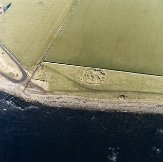 Oblique aerial view of the remains of the broch, buildings, pillbox and slipway, taken from the SE.