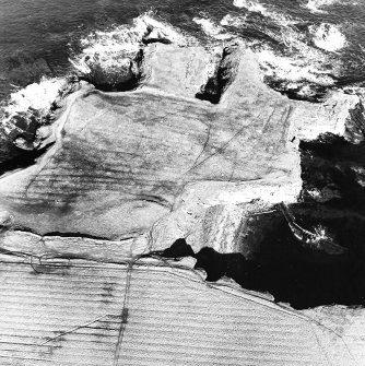 Oblique aerial view of the remains of the fort, chapel, harbour and rig, taken from the S.