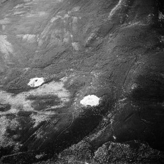 Oblique aerial view centred on the remains of the cairns and boundary stone, taken from the NNW.