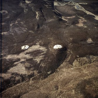 Oblique aerial view centred on the remains of the cairns and boundary stone, taken from the NNE.