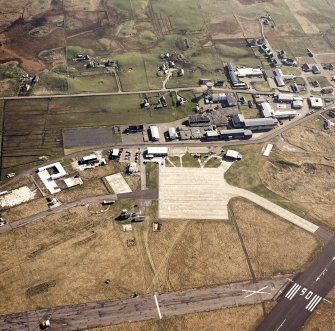 Oblique aerial view centred on the village with the airfield adjacent, taken from the NNE.