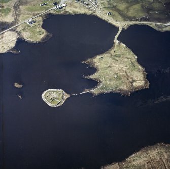 Oblique aerial view centred on the remains of the dun and the buildings, taken from the SE.