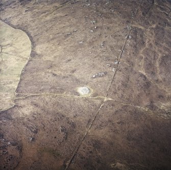 Oblique aerial view centred on the remains of the chambered cairn, taken from the E.