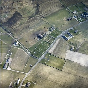 Oblique aerial view centred on the remains of the chapel and the burial enclosure, with the farmsteads and the farmsteadings adjacent, taken from the N