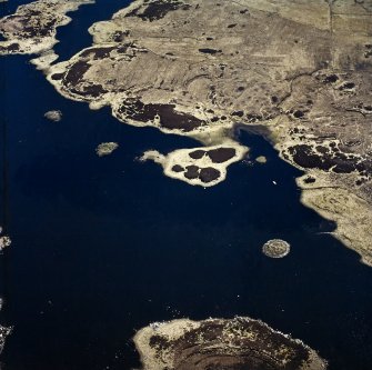 Oblique aerial view centred on the remains of the duns, taken from the NNE.