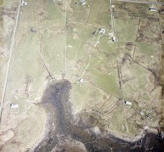 Oblique aerial view centred on the remains of the buildings with the remains of the chambered cairn and standing stone adjacent, taken from the SW.