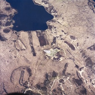 Oblique aerial view centred on the remains of the chambered cairn, taken from the SSE.