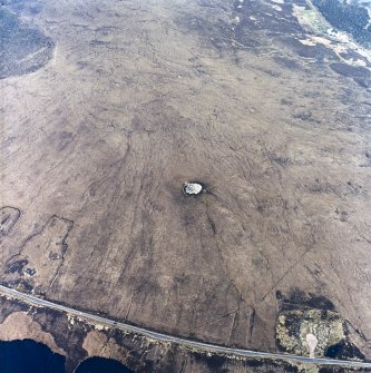 Oblique aerial view centred on the remains of the chambered cairn, taken from the NW.