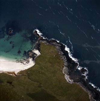 Oblique aerial view centred on the remains of the chapel and broch, taken from the NNW.