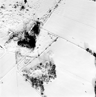 Oblique aerial view of Carn Daley centred on the remains of a chambered cairn with a township adjacent, taken from the S.