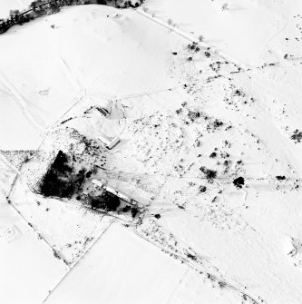 Oblique aerial view of Carn Daley centred on the remains of a chambered cairn with a township adjacent, taken from the E.