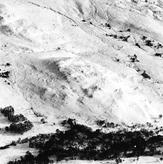 Oblique aerial view of Garbeg centred on the remains of hut-circles, a field-system and small cairns with the same and rig adjacent, taken from the NW.